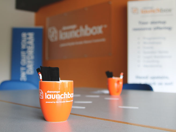 Shenango LaunchBox mug on a table with other LaunchBox advertising materials blurred out in the background