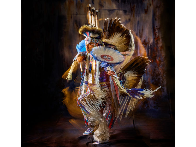 Supaman wearing beautiful traditional Native American clothing and dancing